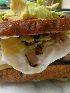 Una foto de Sándwich de pan integral atún, cebolla, aguacate y huevo frito