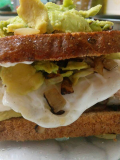 Una foto de Sándwich de pan integral atún, cebolla, aguacate y huevo frito