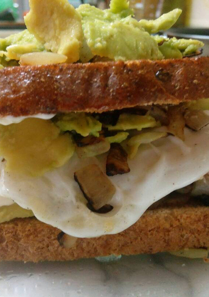 Una foto de Sándwich de pan integral atún, cebolla, aguacate y huevo frito
