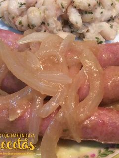 Una foto de Salchichas encebolladas con alubias blancas salteadas