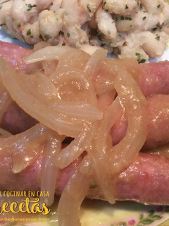 Una foto de Salchichas encebolladas con alubias blancas salteadas