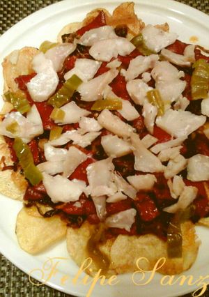 Una foto de Cama de patatas chips con pimientos y bacalao. 