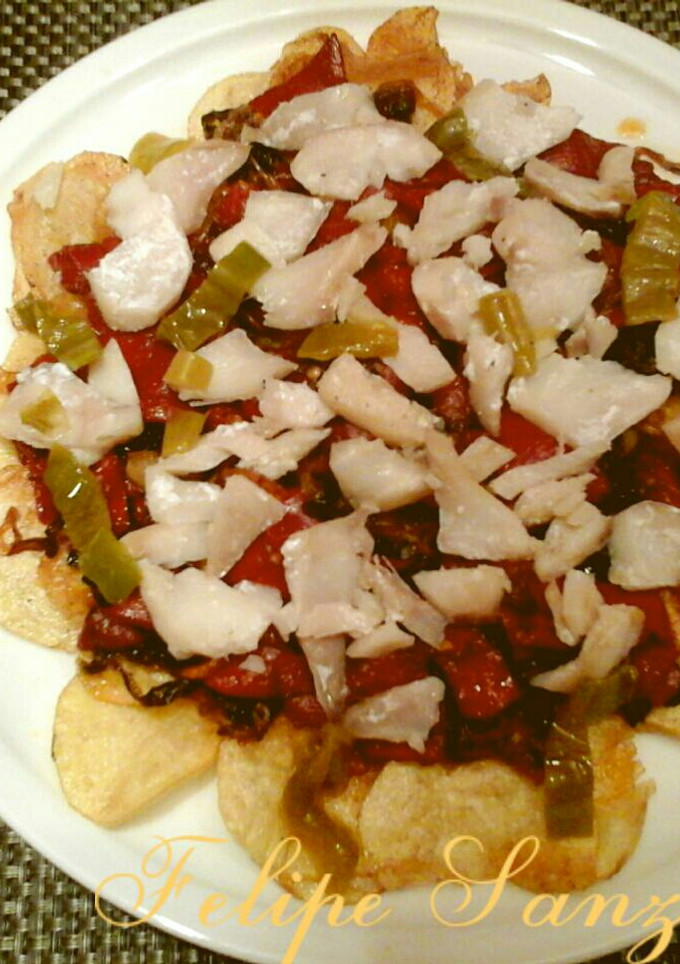 Una foto de Cama de patatas chips con pimientos y bacalao. 