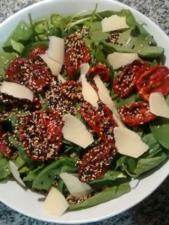 Una foto de Ensalada verde con tomates secos, provolone y semillas de sésamo