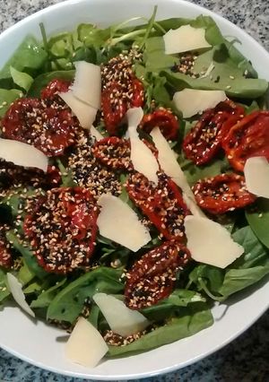 Una foto de Ensalada verde con tomates secos, provolone y semillas de sésamo