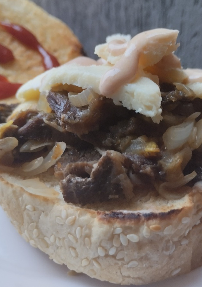 Una foto de Sándwich de carne🥩, cebolla🧀caramelizada🌰 y queso🥯