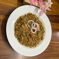 A picture of Desi style fried rice with green chutney.