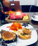 Berenjena rellena de dos carnes con ensalada de pimientos y pan de ajo