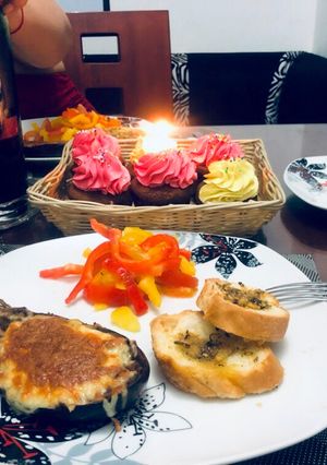 Una foto de Berenjena rellena de dos carnes con ensalada de pimientos y pan de ajo