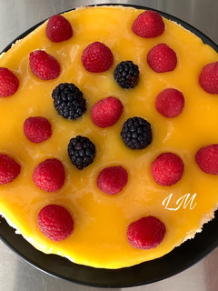 Una foto de Cheesecake con cobertura de mango y frambuesas