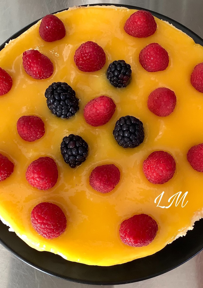 Una foto de Cheesecake con cobertura de mango y frambuesas