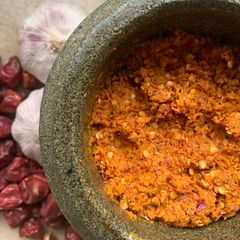A picture of Red Coconut chilli chutney in pestle and mortar.
