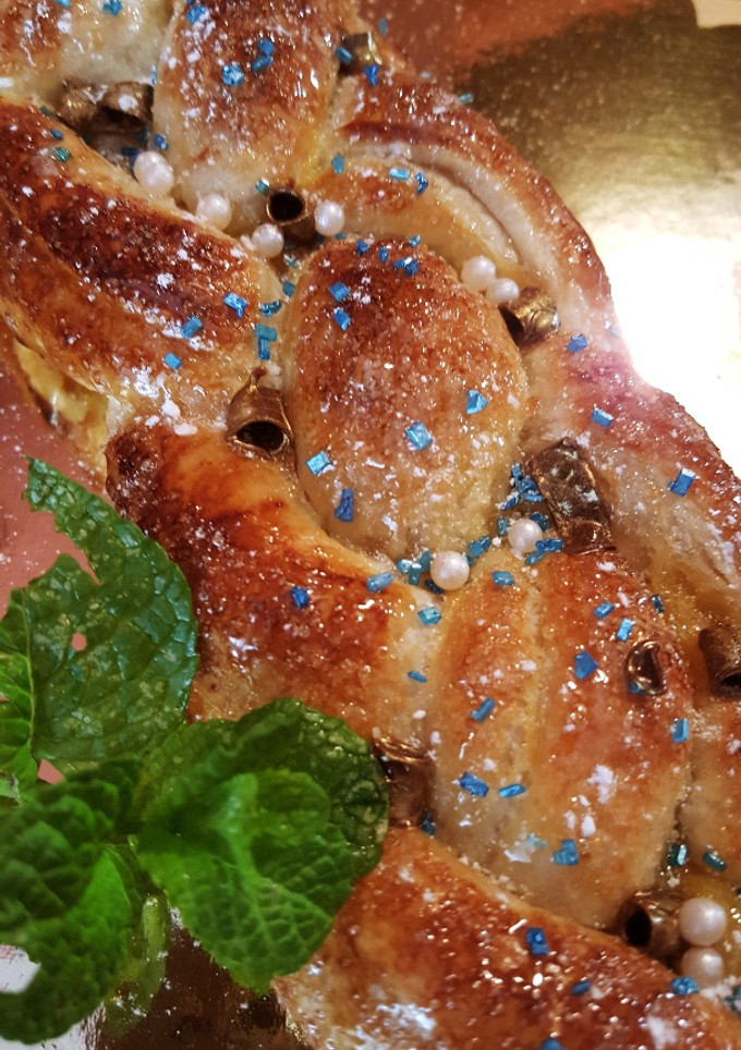 Una foto de Trenza de hojaldre rellena de yema pastelera y uvas pasas