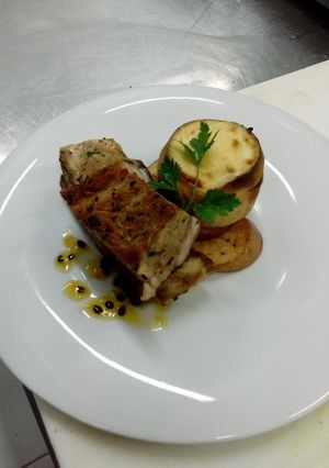 Una foto de Costilla de cerdo y vacuno emulsionada en salsa de maracuyá acompañada de puré de habas envuelto en masa filo gratinado sobre papas al romero