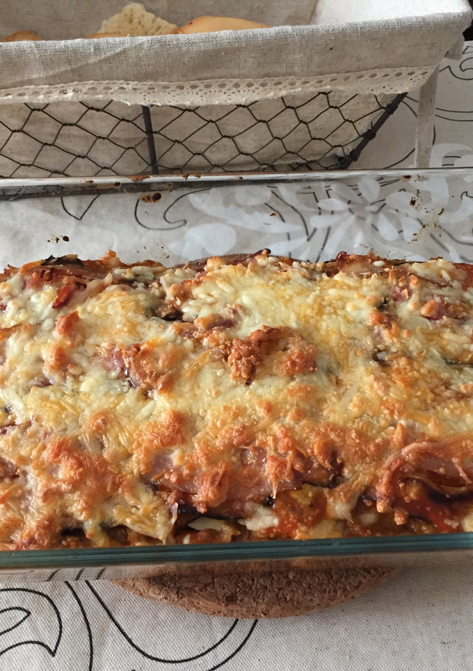 Una foto de Lasaña de berenjena rellena de carne y rulo de cabra con topping de bacon y 4 quesos