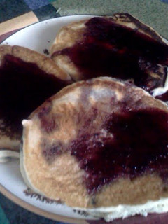 A picture of blueberry pancakes with blueberry syrup.