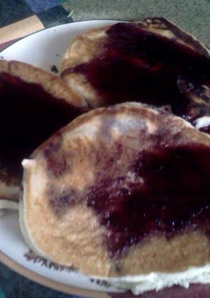A picture of blueberry pancakes with blueberry syrup.