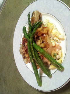 A picture of Bacon Apple Porkchops over loaded mac-n-cheese with Asparagus.