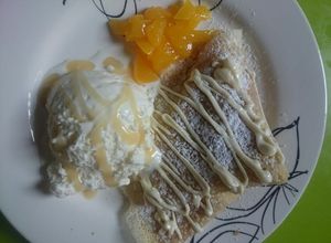 Una foto de Crepes dulces con durazno, dulce de leche y helado
