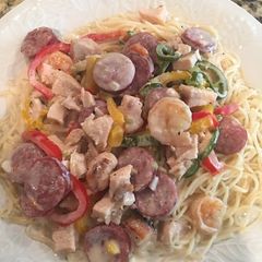 A picture of Chicken, Shrimp, & Sausage with Alfredo Sauce on Angle Hair Pasta.