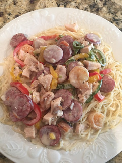 A picture of Chicken, Shrimp, & Sausage with Alfredo Sauce on Angle Hair Pasta.