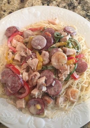 A picture of Chicken, Shrimp, & Sausage with Alfredo Sauce on Angle Hair Pasta.
