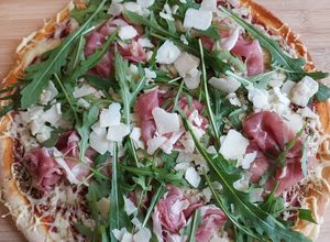 Une photo de Pizza jambon cru, roquette et copeaux de parmesan