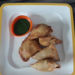 A picture of Aloo Samosa with green chutney.