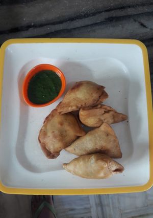 A picture of Aloo Samosa with green chutney.