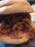 Sándwich de carne desmechada con salsa de vino tinto, salteados y cebolla de verdeo