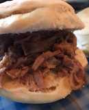 Sándwich de carne desmechada con salsa de vino tinto, salteados y cebolla de verdeo