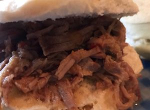 Una foto de Sándwich de carne desmechada con salsa de vino tinto, salteados y cebolla de verdeo