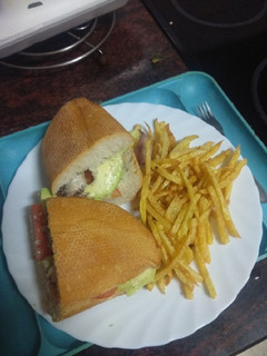 Una foto de Bocadillo de sardinas con aguacate, tomate y papas fritas