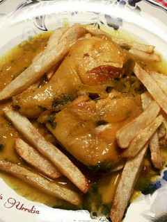 Una foto de Pollo en salsa de cebolla y perejil especiado con patatas fritas