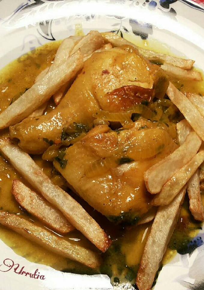 Una foto de Pollo en salsa de cebolla y perejil especiado con patatas fritas
