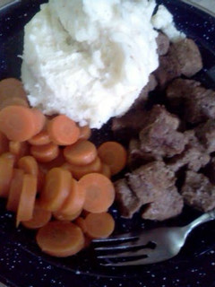 A picture of beef tips with mashed potatoes and carrots.
