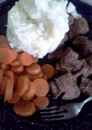 A picture of beef tips with mashed potatoes and carrots.