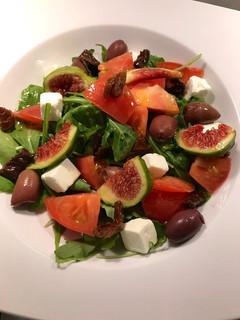 Una foto de Ensalada de tomate, rúcula, queso feta, higos, aceitunas kalamata y tomates secos