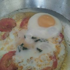 A picture of Sunny side up Eggs with tomato.
