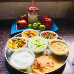 A picture of Ridge gourd Sabzi,Lauki-Channadal,MixedVeg,Curd,Dry Moong dal,Pooris,Fruits.