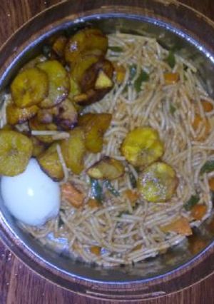 A picture of Spagetti with fried plantain,egg and vegetable.