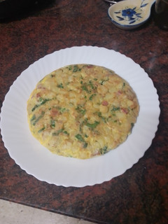 Una foto de Tortilla de papas con cebolla, espinacas y jamón serrano