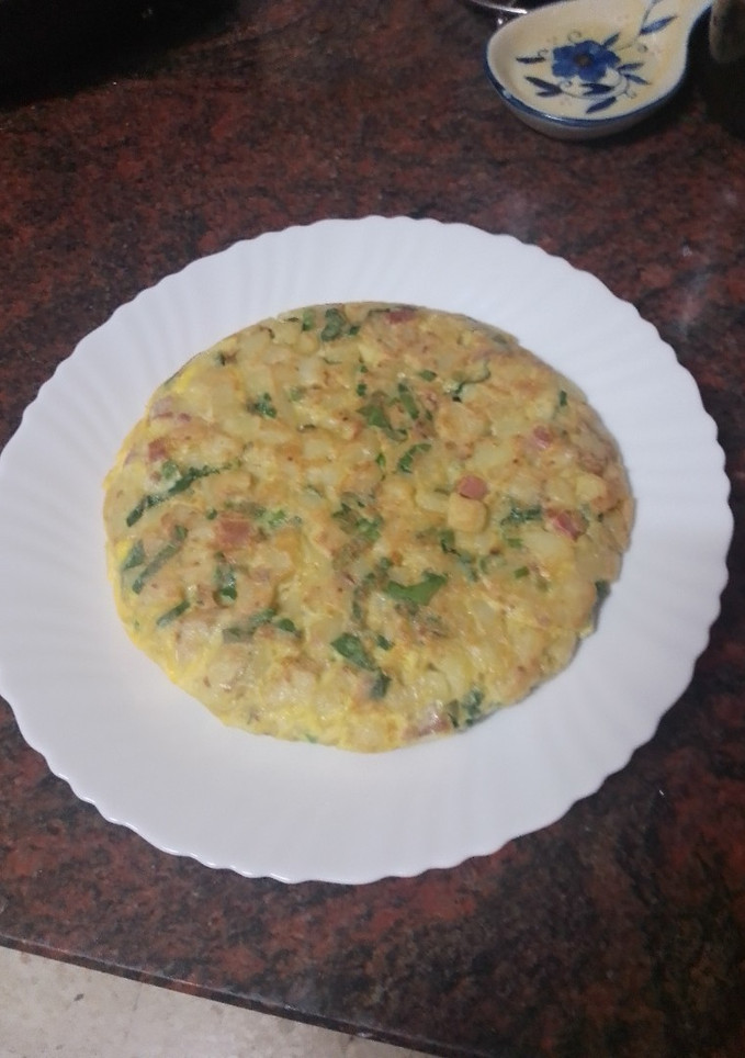 Una foto de Tortilla de papas con cebolla, espinacas y jamón serrano