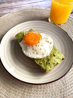 Una foto de Tostadas de guacamole con huevo a la plancha y zumo de naranja