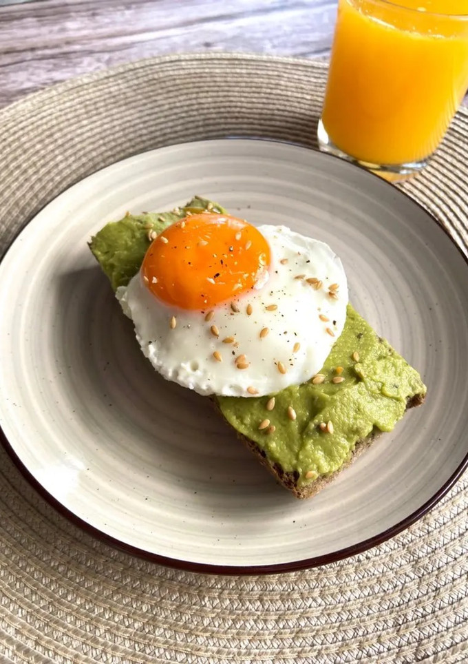 Una foto de Tostadas de guacamole con huevo a la plancha y zumo de naranja