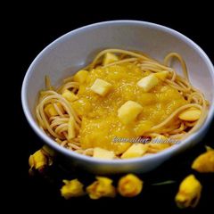A picture of Spaghetti in mango sauce topped with mango cubes.