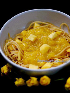 A picture of Spaghetti in mango sauce topped with mango cubes.