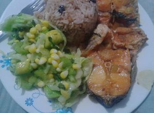 Una foto de Pescado con coco, ensalada y arroz con uvas pasas