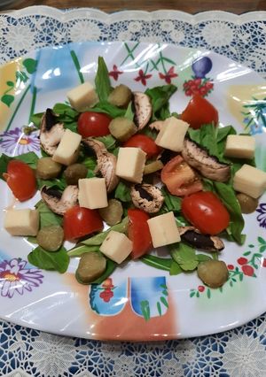 Una foto de Ensalada: rúcula, hongos, cherry, pepinillos y queso