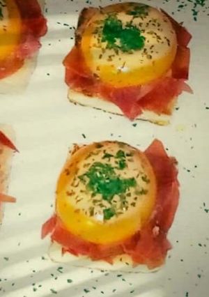 Una foto de Yemas de huevos rellenas de crema de tomate sobre un lecho de jamón ibérico